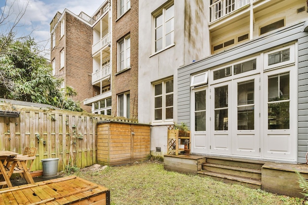 A small backyard overgrown with grass and with a wooden fence