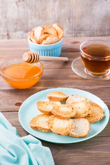 Small baguette toast on a plate on a wooden table Homemade tea with honey