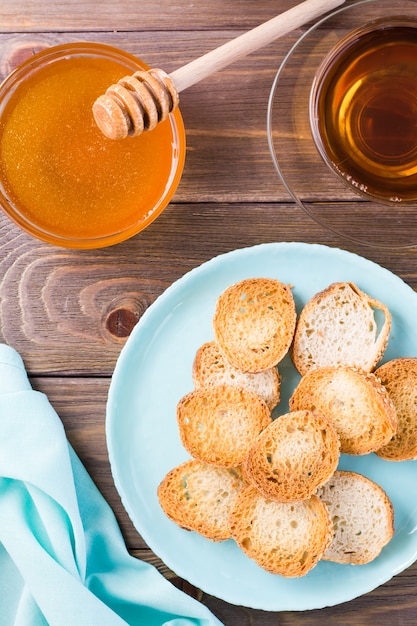 Small baguette toast on a plate on a wooden table Homemade tea with honey