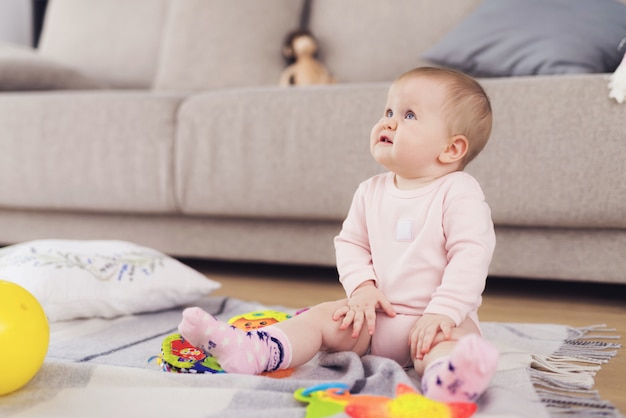 Small beautiful baby sits on the floor and plays 