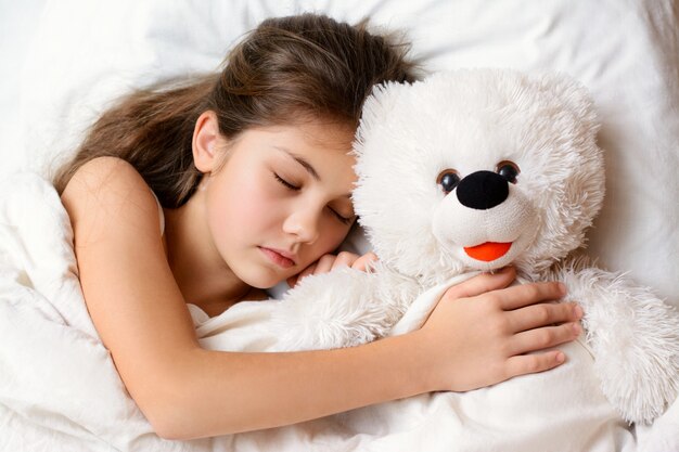 Small beautiful girl hugs her favourite toy while sleeping 