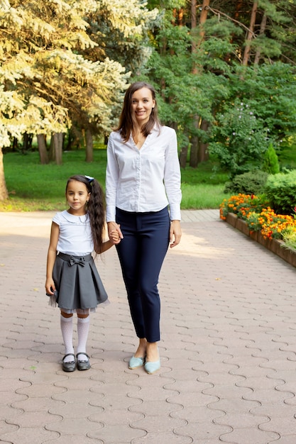 a small beautiful schoolgirl girl with dark hair stands with a young mother