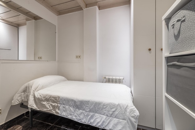 A small bedroom with white walls with wooden coffered ceiling a single bed