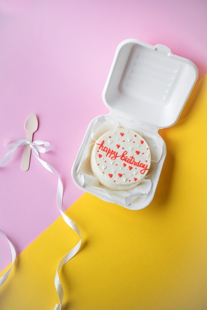 A small bento birthday cake in a box Wooden boat with white ribbon