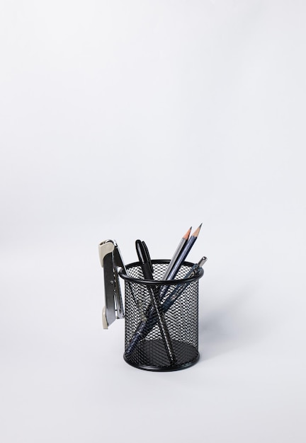 A small black basket made of round steel Can be used to store office supplies including pens pencils stapler and still have space to put more things In the white background there is copy space