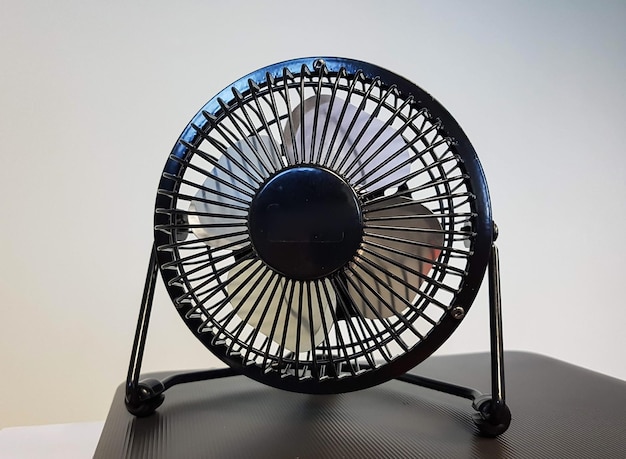 Foto un piccolo ventilatore nero su un tavolo nero con uno sfondo bianco