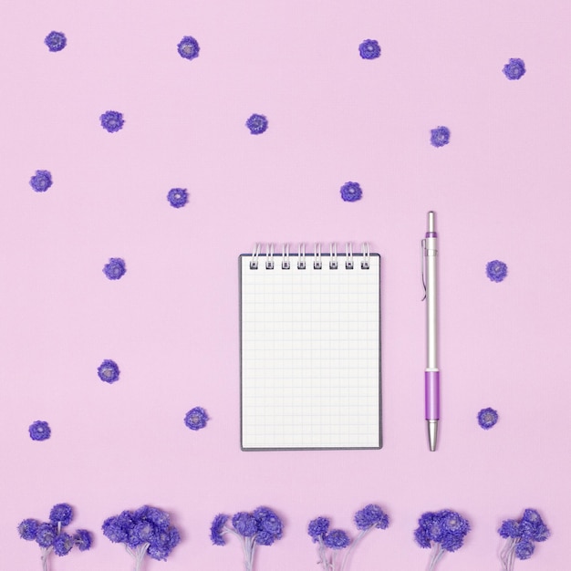 小さな空白のノートペンと花のレイアウトウィッシュリストフェミニンなコンセプト