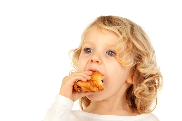 Small blond child eating a croissant