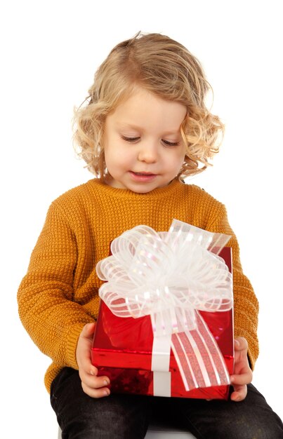 Foto piccolo bambino biondo con un regalo rosso isolato
