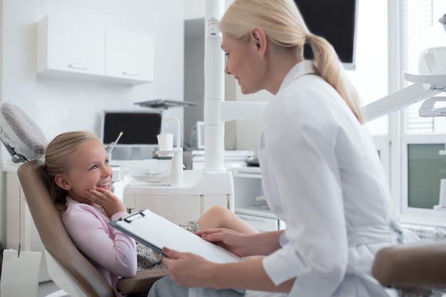 Small blonde girl having an appointment with the pediadontis