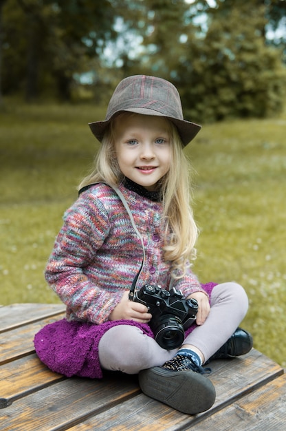 Small blonde girl taking picture using with vintage film camera