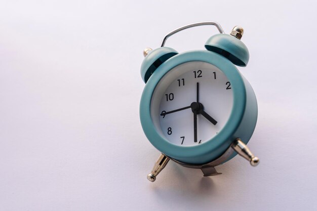 Small blue alarm clock in vintage style on a white background