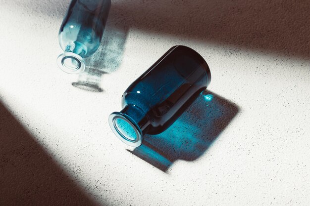 흰색 콘크리트 배경에 작은 파란색 유리 병