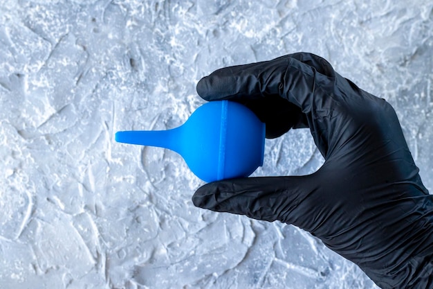 Small blue syringe bulb in hand with medical glove Closeup