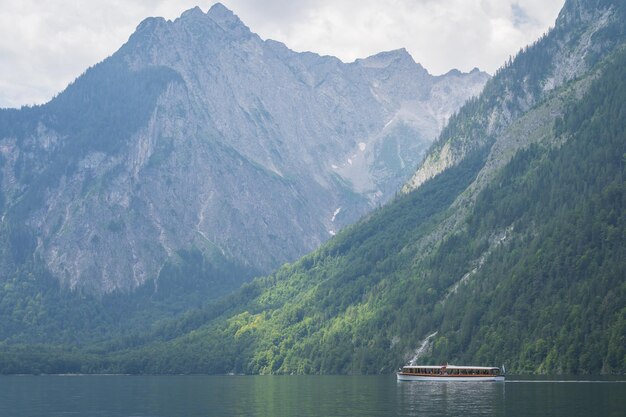 Small boat sailing on alpine lake surrounded by high mountains konigssee germany