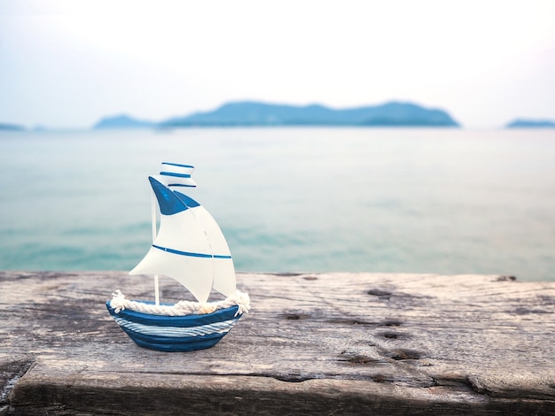 Photo small boat toy on wood plank over sea background.