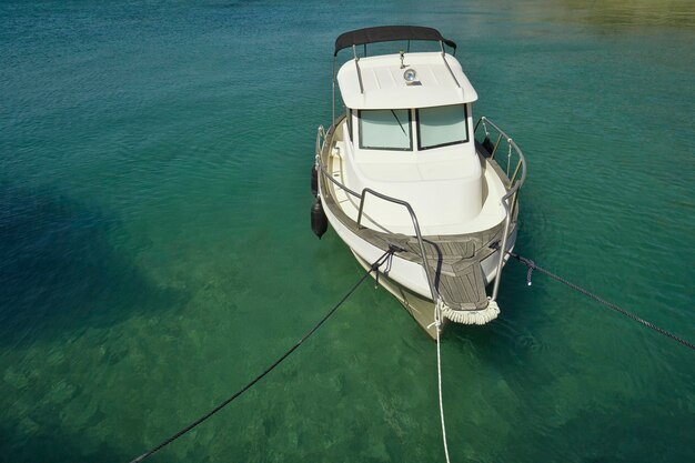 A small boat with cabin and sun roof anchors in the harbor