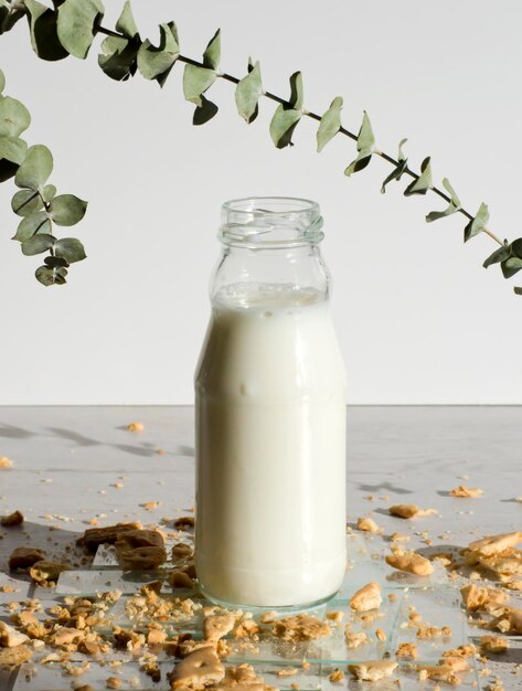 Photo small bottle of milk on transparent sheets and cookie crumbs