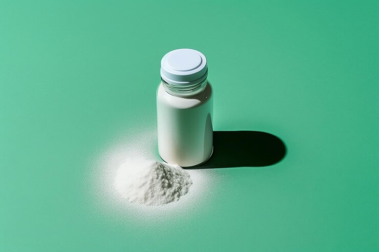 흰색 가루가 든 작은 병이 녹색 표면에 놓여 있습니다.