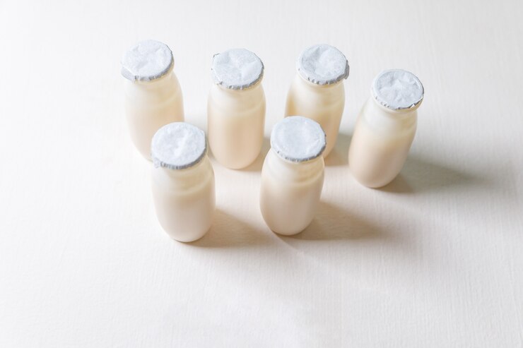 白い背景にプロバイオティクスとプレバイオティクスの乳飲料が入った小瓶。生物学的に活性な添加物による生産。発酵とダイエットの健康食品。有用な微生物を含むバイオヨーグルト。