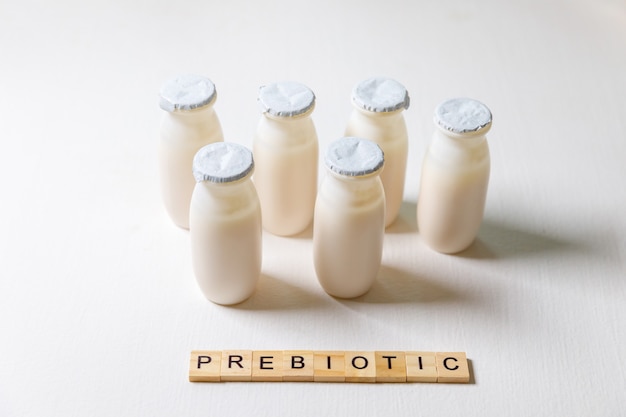 Piccole bottiglie con probiotici e bevande lattiero-casearie prebiotiche su sfondo bianco. produzione con additivi biologicamente attivi. fermentazione e dieta alimentare sana. yogurt biologico con microrganismi utili.