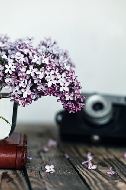 Small bouquet of lilac in glass vase as detail of interior, on wood background