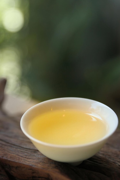 A small bowl of yellow liquid sits on a wooden table.