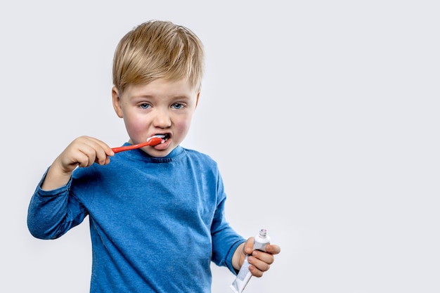 A small boy brushes his teeth on his own