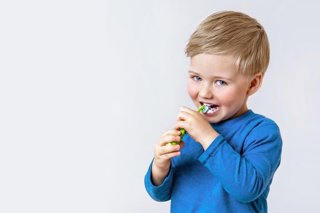 A small boy brushes his teeth on his own