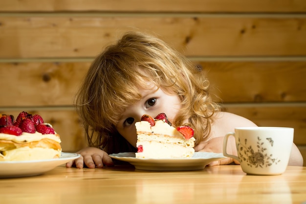 Photo small boy eats strawberry cake