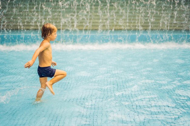 Маленький мальчик с удовольствием работает в бассейне