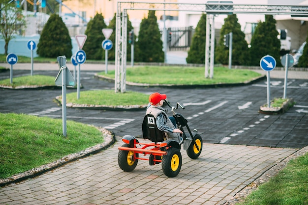 小さな男の子は庭でおもちゃの車を運転しています。