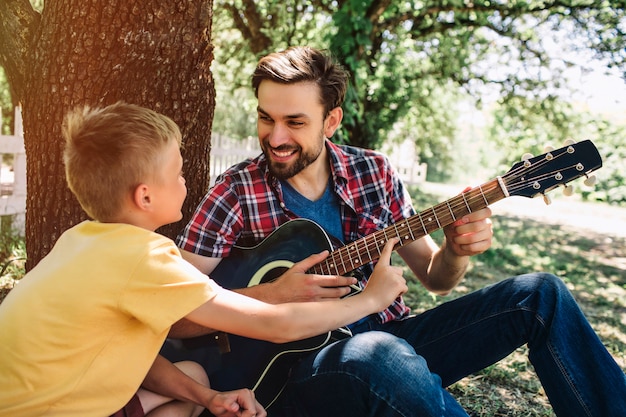 小さな男の子は父親のギターに傾いています