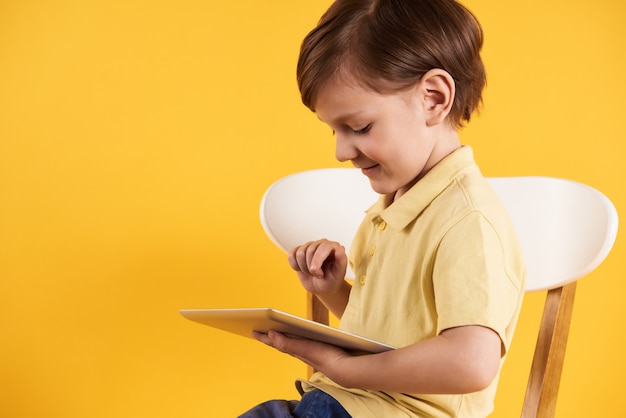 Small boy is typing on computer tablet