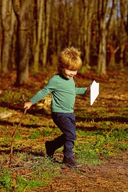 Foto piccolo ragazzo lancia aereo di carta giocattolo all'aperto piccolo bambino gioca con il giocattolo nel parco tempo per risparmiare andare in aereo