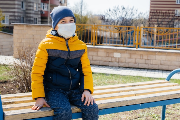 A small boy in a mask walks on the Playground during the quarantine. Stay at home