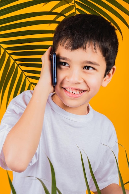 Small boy talking with smartphone on yellow background.