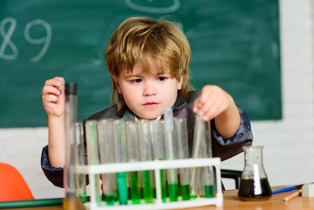 Small boy using microscope at school lesson small boy study\
chemistry result medical concept little genius child testing tubes\
with liquid for research learn for future research development