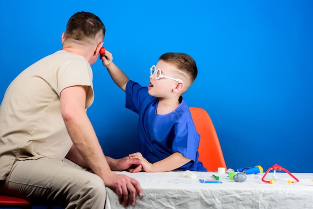 Small boy with dad in hospital family doctor medicine and health happy child with father with stethoscope father and son in medical uniform dad play with his son dad is doctors patient