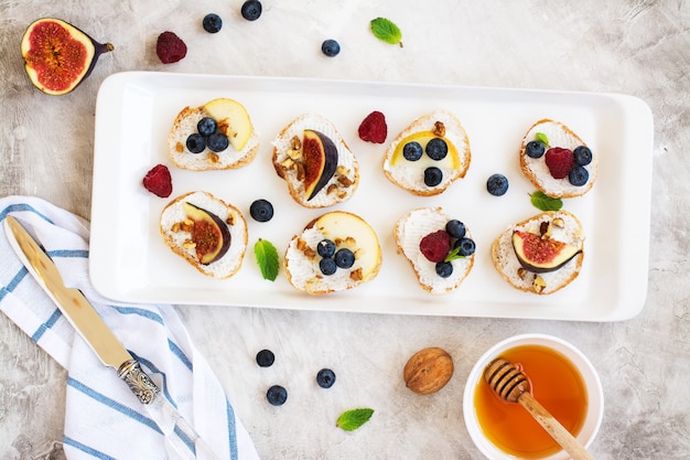 Small bruschetta with berries, honey, ricotta and mint