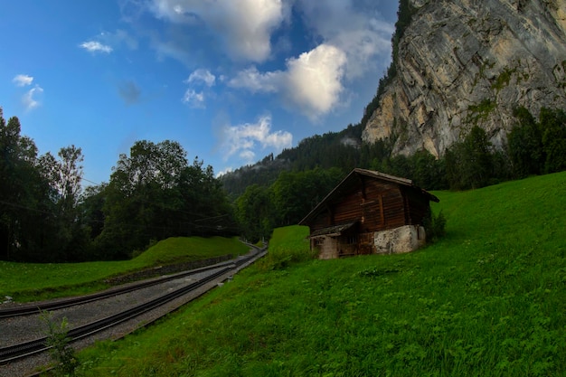 Photo a small building sits in the grass near a mountain