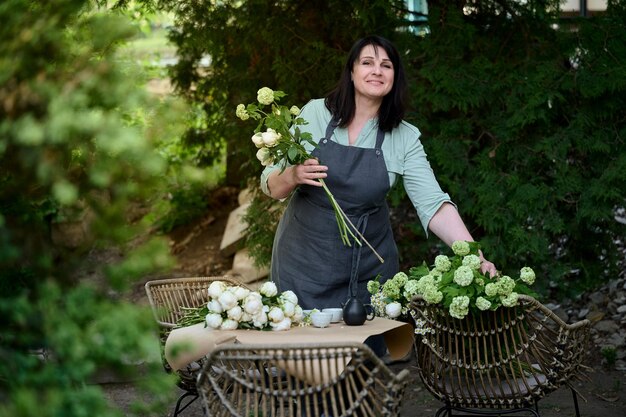 녹색 테라스에 있는 중소 기업의 아름다운 수석 꽃집은 꽃다발을 만든다