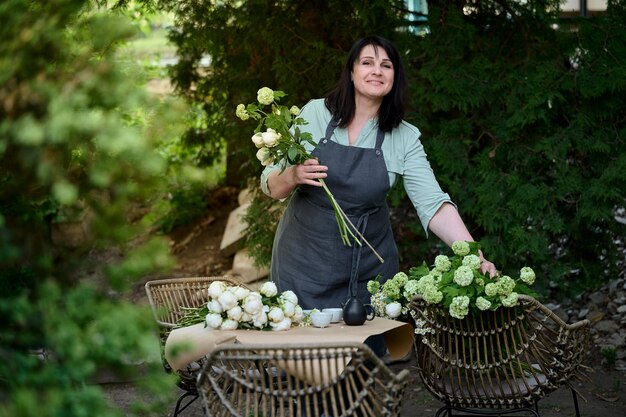 緑のテラスで中小企業の美しいシニア花屋は花束を作ります