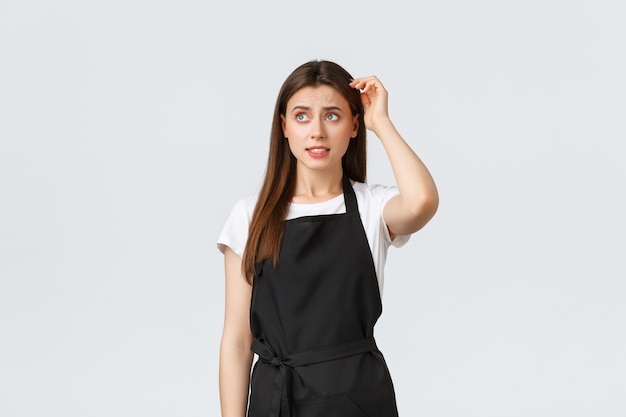 Small business and coffee shop concept. Clueless indecisive barista scratch head and looking worried. Anxious cafe worker have problem thinking. Saleswoman at grocery store standing puzzled.