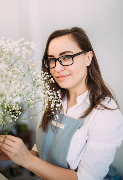 Small business. Florist girl is focused in a flower shop. Bright studio of floral design, decor. Flower delivery, order creation