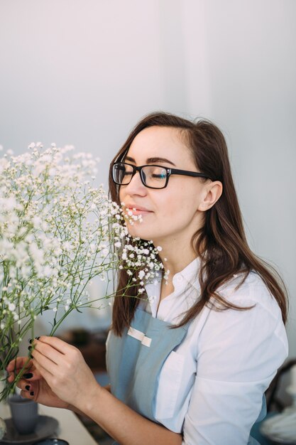 Small business. Florist girl is focused in a flower shop. Bright studio of floral design, decor. Flower delivery, order creation