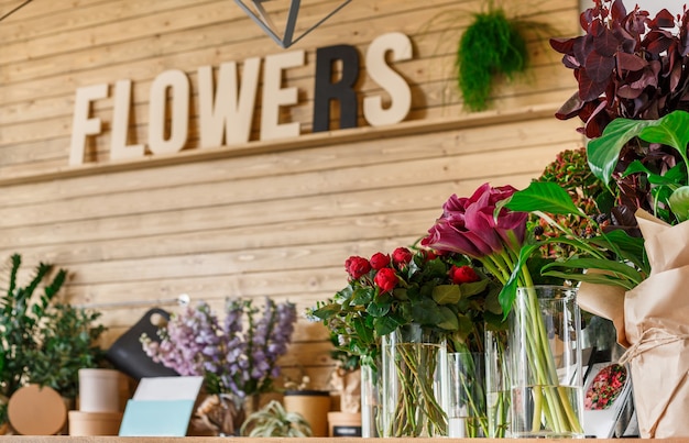Small business. Modern flower shop interior. Floral design studio, sale of decorations and arrangements. Flowers delivery service and sale of home plants in pots, wooden showcase.