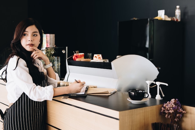 small business owner barista wearing apron writing note in cafe