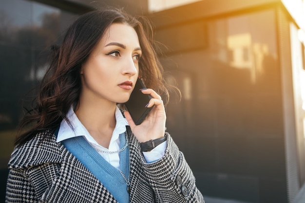 Small business owner office worker woman outside hold mobile phone chatting colleague speaking