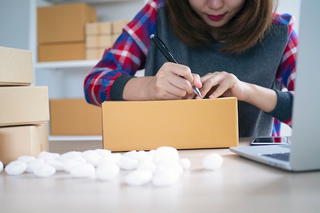 Small business owners are writing names to prepare to deliver packages to customers. Small businesses selling online and ordering products online